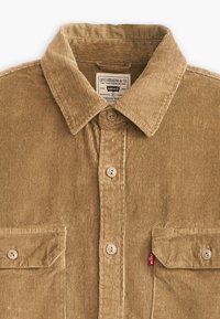 Brown corduroy shirt featuring a collar, front button closure, and two chest pockets with button flaps. Small red Levi's tag on the side.