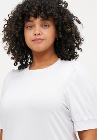 White cotton t-shirt with a round neck and short puff sleeves. The fabric appears smooth, lightweight, and slightly textured.
