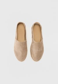 Beige velúr slip-on cipők lekerekített orral, varrott szélekkel és sima bélésse. A talp texturált felületű, ami jó tapadást biztosít.