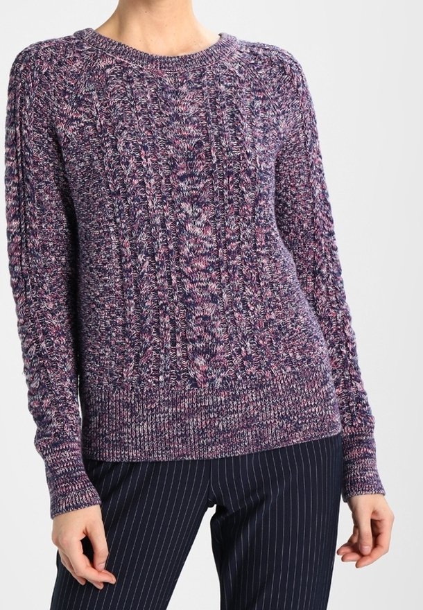 Maglione a maglia viola con un motivo texturizzato e polsini a coste, con scollatura rotonda. Abbinato a pantaloni a righe.