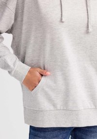 Sudadera gris hecha de tela suave, con un bolsillo frontal, puños acanalados y capucha con cordón. El diseño es casual y de corte relajado.