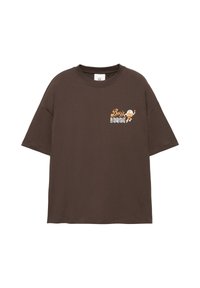 T-shirt marron foncé à manches courtes avec un petit motif d'astronaute orange et blanc et le mot "Buzz" sur la partie supérieure gauche de la poitrine.