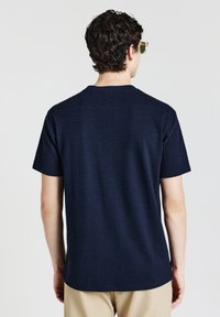 Camicia a maniche corte blu navy con tessuto testurizzato. Collo rotondo, taglio dritto e dettagli minimi. Adatta per un abbigliamento casual.