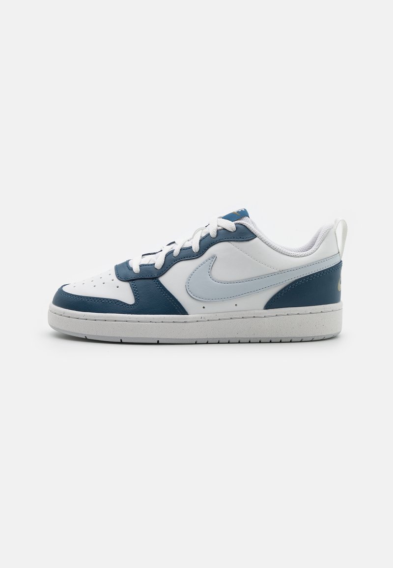 Baskets en cuir blanches et bleu marine avec une surface texturée, un bout perforé, des lacets blancs et un logo swoosh Nike bleu clair.