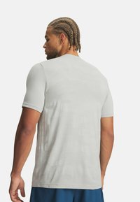 Camiseta deportiva de manga corta en gris claro con una textura suave y un patrón sutil. Presenta un escote redondo y un ajuste relajado.