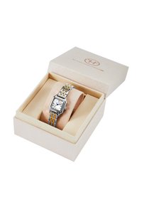Montre carrée en métal argenté et doré avec un cadran blanc, présentée dans une boîte à bijoux rembourrée beige. La boîte a un logo en relief sur le couvercle.
