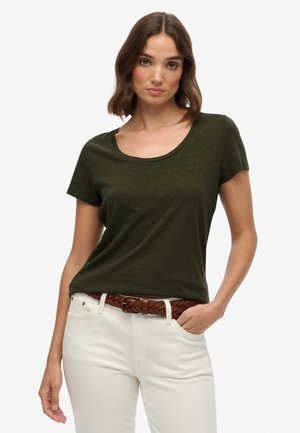 Olijfgroene T-shirt met korte mouwen en een ronde halslijn, voorzien van een subtiele logodetail, gecombineerd met witte broek en een gevlochten bruine riem.