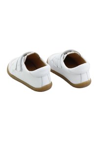 Zapatos infantiles blancos con correas de Velcro, parte superior de cuero suave, punta redondeada y suela de goma. Diseño sencillo con un detalle mínimo.