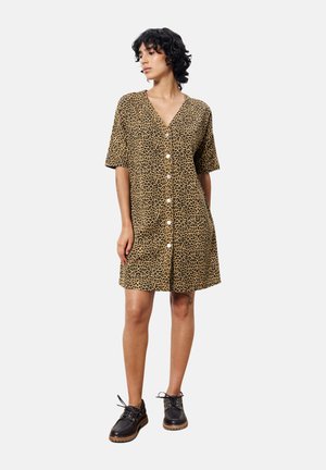 Leopardprint shirtjurk in bruin en zwart, met korte mouwen en een V-hals, gecombineerd met zwarte veterschoenen.