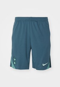 Miesten urheilushortsit tumman tealinsinisissä sävyissä, valmistettu hengittävästä kankaasta, jossa on tekstuuroitu pinta. Varustettu seuran logolla ja vaaleanvihreällä Nike-logolla.