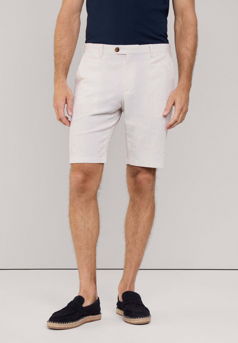 Pantaloni corti a righe in tonalità chiare, dal taglio comodo, realizzati in un tessuto traspirante, con chiusura a bottone e tasche a filetto. Abbinate a calzature nere.