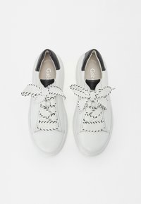 Sneaker bianche in pelle con dettagli neri sul tallone, dotate di lacci larghi a strisce nere e bianche, punta rotonda e imbottitura interna.