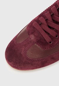 Bottines en daim bourgogne avec des accents en cuir, bout rond et design de laçage texturé. Coutures visibles et détails de surface lisses.