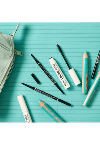Crayons eye-liner bleus, crayons à sourcils noirs, tubes de mascara blancs et une trousse zippée vert clair sur un fond rayé bleu.