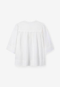 Weiße Baumwollbluse mit lockerer Passform, ausgestattet mit einem geplotteten Rückendesign und Dreiviertelärmeln. Schlichte runde Halslinie, keine zusätzlichen Details.