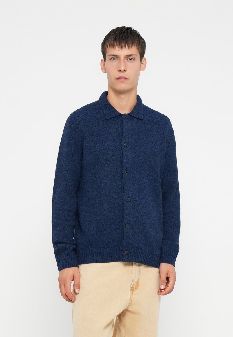 Cardigã malha azul-marinho com colarinho, botões frontais e punhos e barra em ribanas. Textura suave e ajuste descontraído.