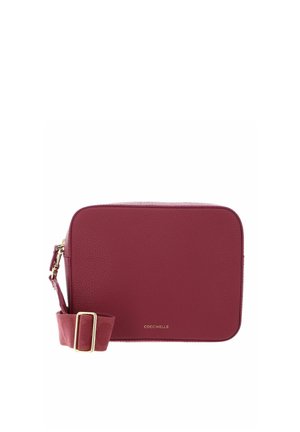 Sac bandoulière rectangulaire en cuir bordeaux avec sangle ajustable et boucle dorée, petit logo de la marque au centre avant.