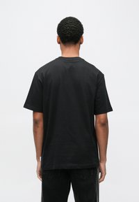 Melna īsroku krekls ar klasisku apaļu apkakli, izgatavots no mīksta kokvilnas auduma. Piedāvā ērtu piegriezumu un nelielu etiķeti apakšā.