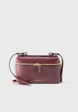 Bordová kožená kabelka na crossbody so zlatým zipsom, dvojitými ťaháčikmi na zips, nastaviteľným remienkom a zlatým logom „Victoria Beckham“ na prednej strane.