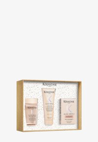 Set de regalo Kérastase Gloss Absolu que incluye tres productos: un tarro rosa, un tubo y una caja rectangular, todos en suaves tonos pastel, presentados en una caja salpicada de oro.
