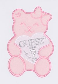 Pink embroidered bear with a heart, featuring "GUESS" in silver. Bear has a bow on its head and subtle facial details, set on a white background.