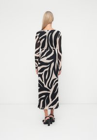 Robe maxi à manches longues en tissu transparent avec un motif zebra beige et noir, dotée d'une silhouette ajustée et d'un ourlet droit.