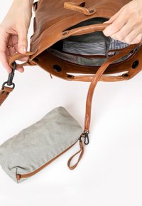 Borsa tote in pelle marrone con una sacca in tessuto a righe. Interno foderato con motivo a righe, presenta una chiusura a scatto e dettagli con tracolla regolabile.