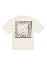 Camiseta de manga corta en color crema con intrincados diseños en negro de paisley y flores centrados en la parte posterior dentro de un borde cuadrado.