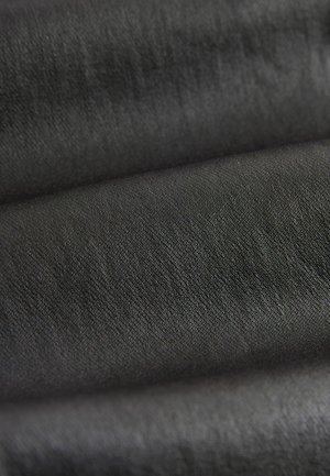 Textil i svart, med en slät yta och en subtil lyster. Tyget har en tät väv, vilket visar på små variationer i djup.