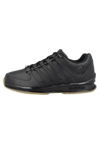 Black synthetic athletic shoe with a textured surface, featuring three horizontal stripes, a rubber sole, and a logo on the side.