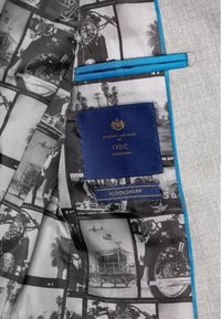 Szara podszewka kurtki z czarno-białymi fotografiami, z niebieskim akcentem i niebieską metką z napisem "Zaprojektowane i wyprodukowane przez Next."