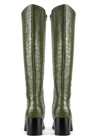 Bottes vertes brillantes montant au-dessus du genou, avec une texture crocodile, un talon carré et une fermeture éclair à l'arrière. Accentuées par des lignes horizontales.