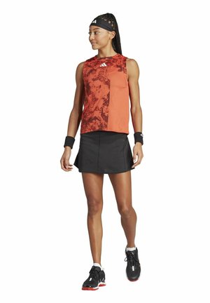Les vêtements de tennis comprennent un haut sans manches rouge avec un design à motifs et une jupe noire. Les accessoires incluent des bandeaux et des chaussures de tennis noires.