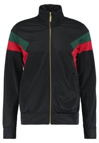 Svart zip-up träningsjacka med hög krage, med gröna och röda diagonala ränder på axlarna och guldblixtlås. Slät, glänsande tyg.