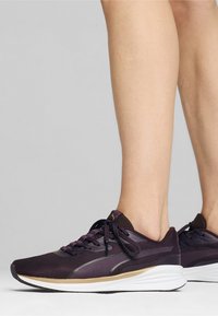 Zapatillas deportivas moradas con parte superior de malla, cordones a juego, suela de goma y acentos reflectantes. Diseñadas para la comodidad y el rendimiento.