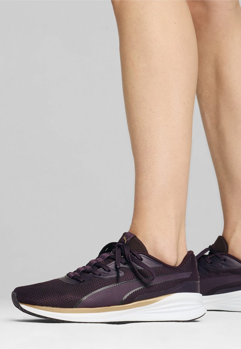 Zapatillas deportivas moradas con parte superior de malla, cordones a juego, suela de goma y acentos reflectantes. Diseñadas para la comodidad y el rendimiento.