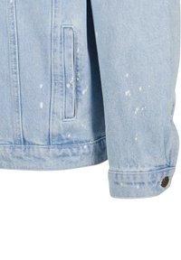 Light blue denim jacket featuring white paint splatter, two side pockets, and button detail on the sleeve cuff. Classic fit and texture.