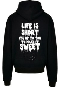 Črna kapuca z teksturiranim sprednjim delom, na katerem je bel, kapljajoč napis: "ŽIVLJENJE JE KRAJŠE, OD TEBE JE ODVISNO, DA GA OMAKEŠ SLADKO" in logotip nasmejane obraza.