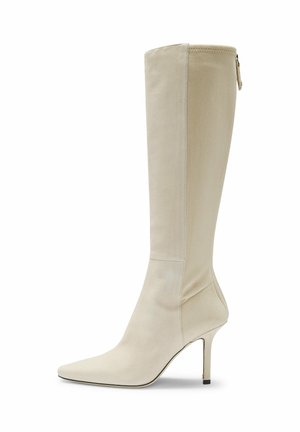 Botte beige montante jusqu'au genou en tissu doux, à talon haut, avec un bout pointu et une silhouette élégante. Détail de fermeture éclair latérale et finition lisse.