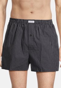Schwarz-weiße karierten Boxershorts aus leichtem Stoff, mit einem elastischen Bund, Knopfverschluss und lockerem Schnitt.