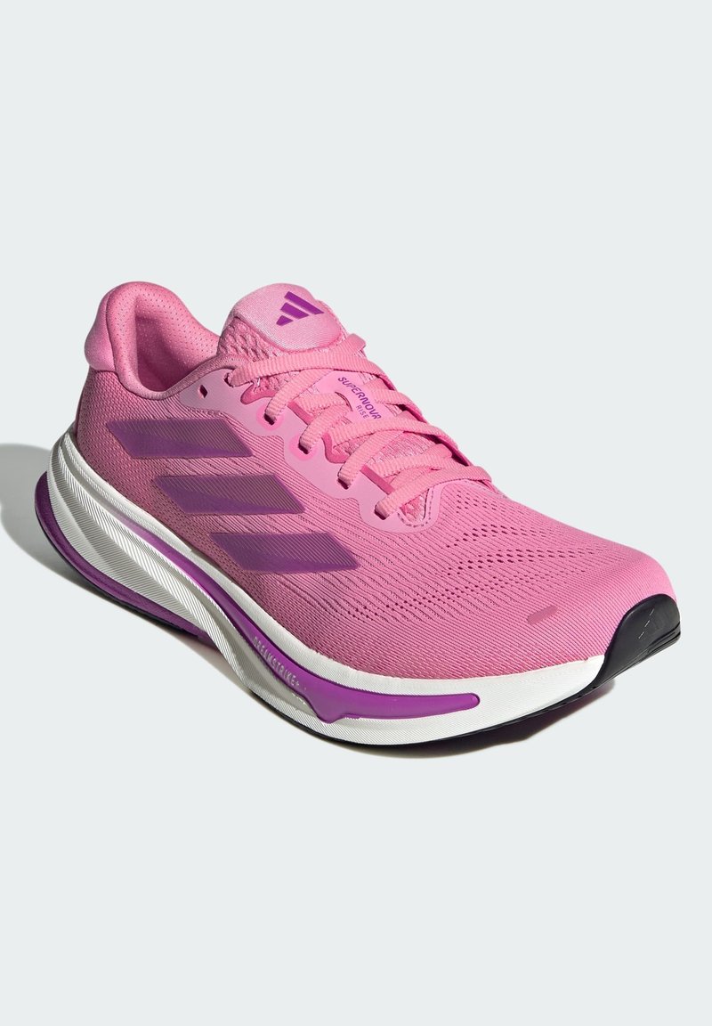 Baskets de sport roses avec tige en mesh respirant, trois rayures rose foncé, semelle intermédiaire blanche et violette, et semelle extérieure en caoutchouc noir.