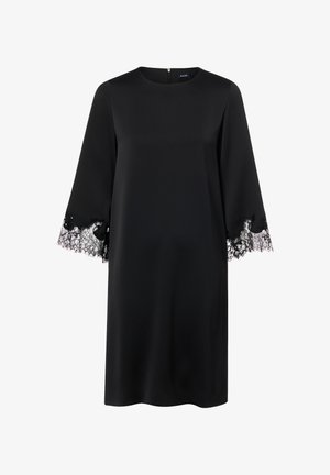 Schwarzes Kleid mit rundem Ausschnitt und Spitzenbesatz an den Ärmelabschlüssen. Hergestellt aus glattem Stoff mit entspannter Silhouette. Reißverschluss am Rücken.