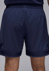 Pantaloni sportivi blu navy realizzati in tessuto leggero, con vita elasticizzata e dettagli laterali. Texture liscia con lunghezza a metà coscia.