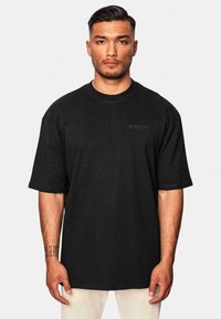 Sort oversized T-shirt lavet af bomuld. Den har en rund halsudskæring og korte ærmer, med tekstureret broderi "dripsize" på brystet.