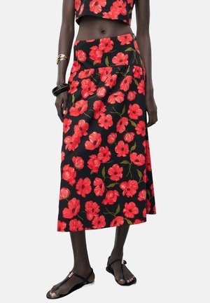 Floral skirt in black fabric, featuring red poppy patterns, mid-length design, and a flared silhouette. Paired with a matching crop top.