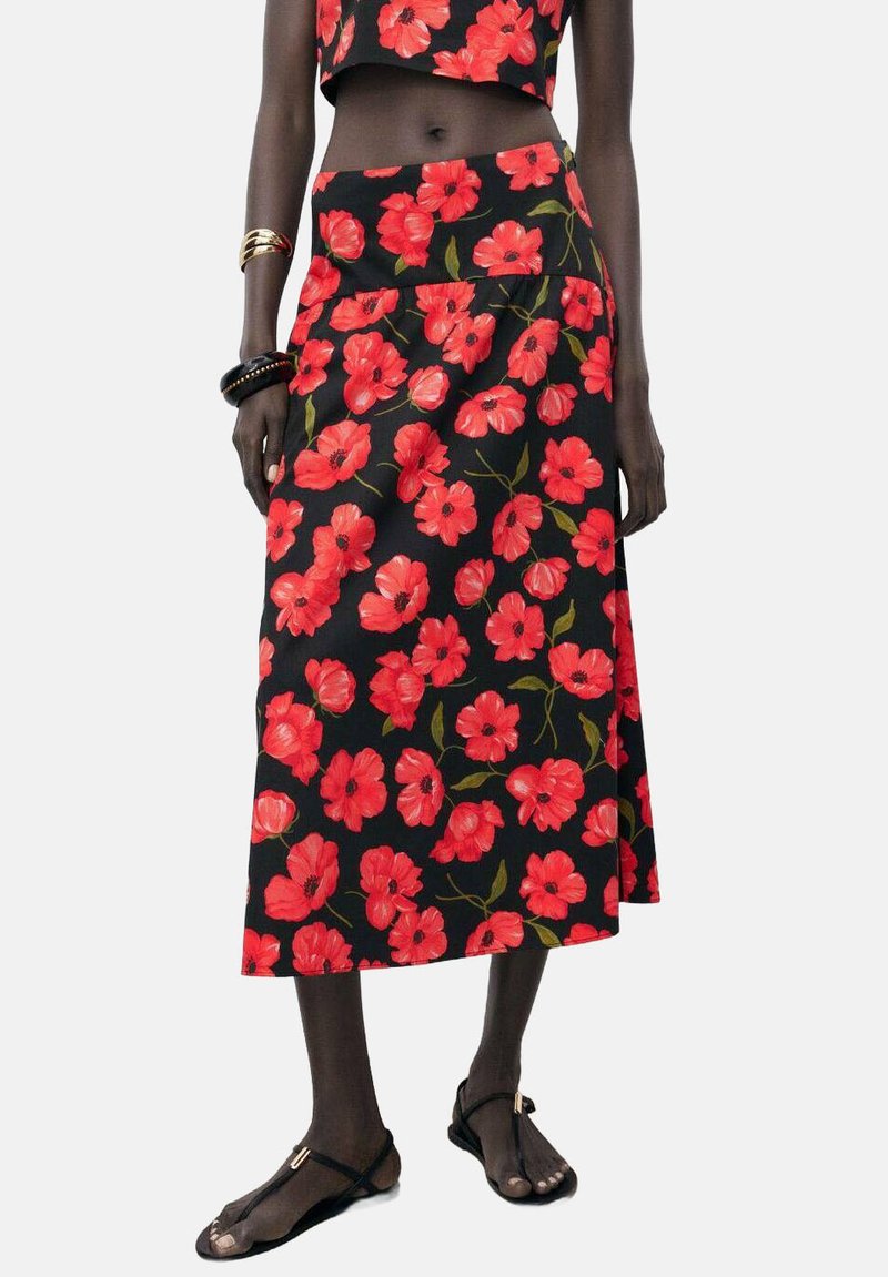 Floral skirt in black fabric, featuring red poppy patterns, mid-length design, and a flared silhouette. Paired with a matching crop top.