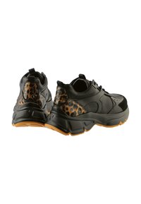 Schwarze Sneakers mit einer strukturierten Oberseite, Leopardenmuster-Akzenten an der Ferse und einer klobigen Gummisohle mit einem kontrastierenden orangefarbenen Rand.