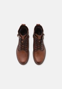 Stivali ankle in pelle marrone con finitura testurizzata, dotati di lacci e cerniera laterale. Punta arrotondata e dettagli di cucitura a contrasto.