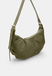 Borsa a spalla in suede verde oliva con forma curva, chiusura a zip, tracolla regolabile e accenti di metallo minimalisti.