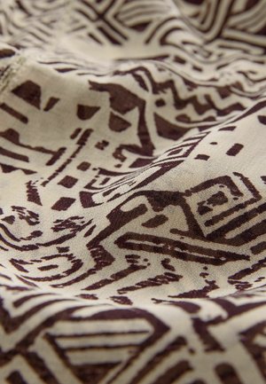 Tessuto con motivo a sfondo astratto geometrico in marrone scuro su uno sfondo beige chiaro, che presenta una superficie liscia e strutturata.